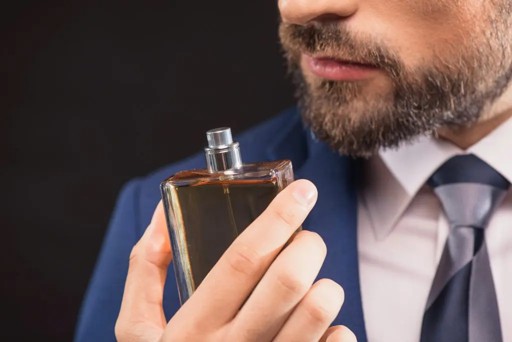 Homem sentindo cheiro de um perfume