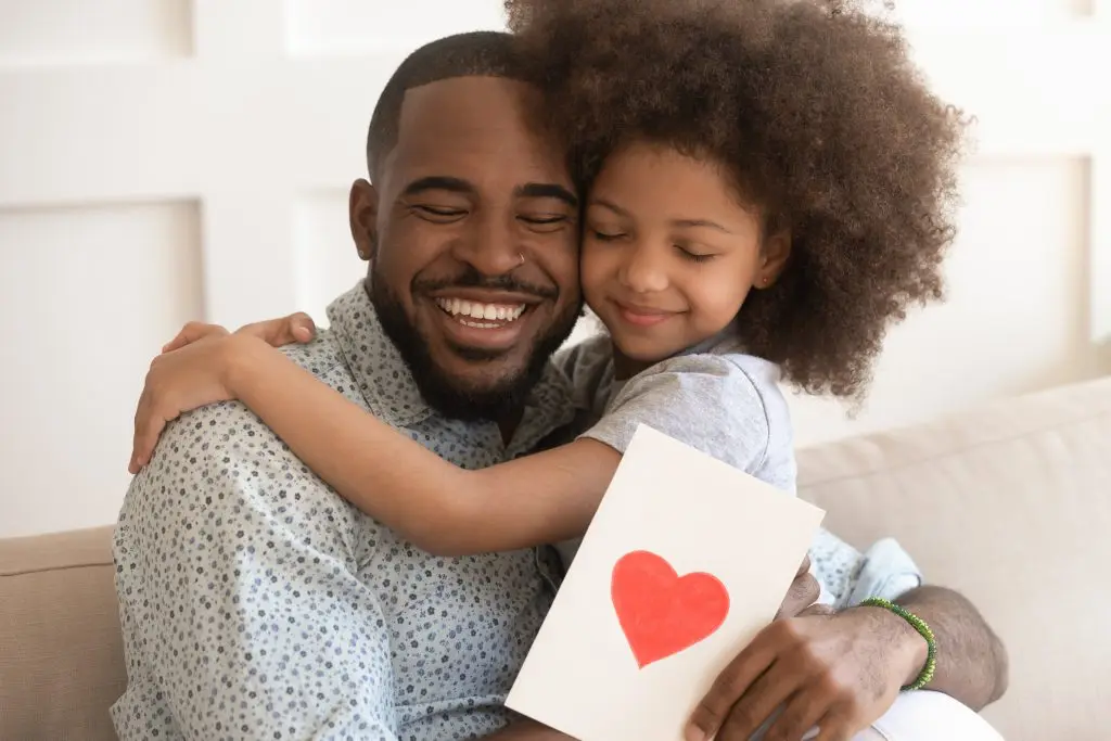 Pai abraçando a filha por ter ganho um presente